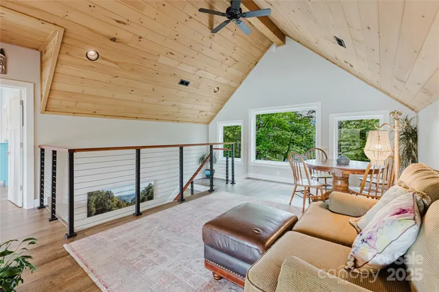 a living room with furniture large windows and wooden floor