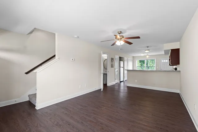 a view of an empty room with wooden floor and a ceiling fan