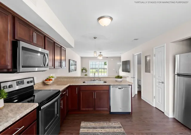 a kitchen with stainless steel appliances granite countertop a stove top oven a sink dishwasher a refrigerator and cabinets with wooden floor