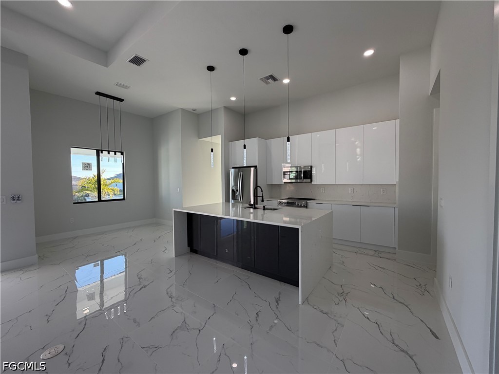 112 Northeast 6th Street Cape Coral, FL 33909 - Photo 5 of 37 a large white kitchen with kitchen island a sink a stove a counter space and cabinets
