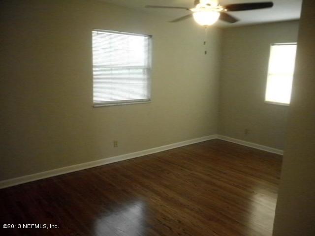 3902 Heidi Road West Jacksonville, FL 32277 - Photo 13 of 24 an empty room with wooden floor and windows