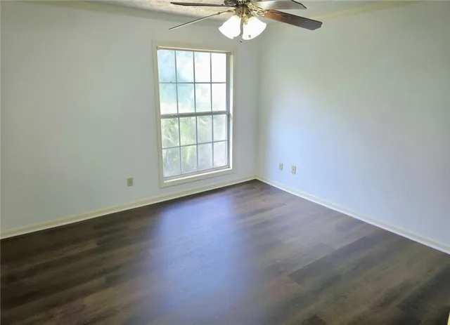 an empty room with wooden floor fan and window