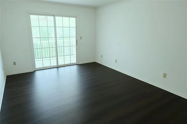an empty room with wooden floor and windows with curtains