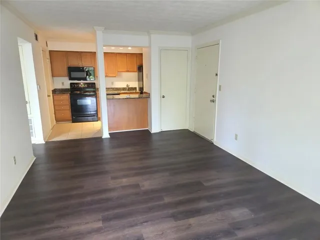 a view of a kitchen with wooden floor electronic appliances and cabinets