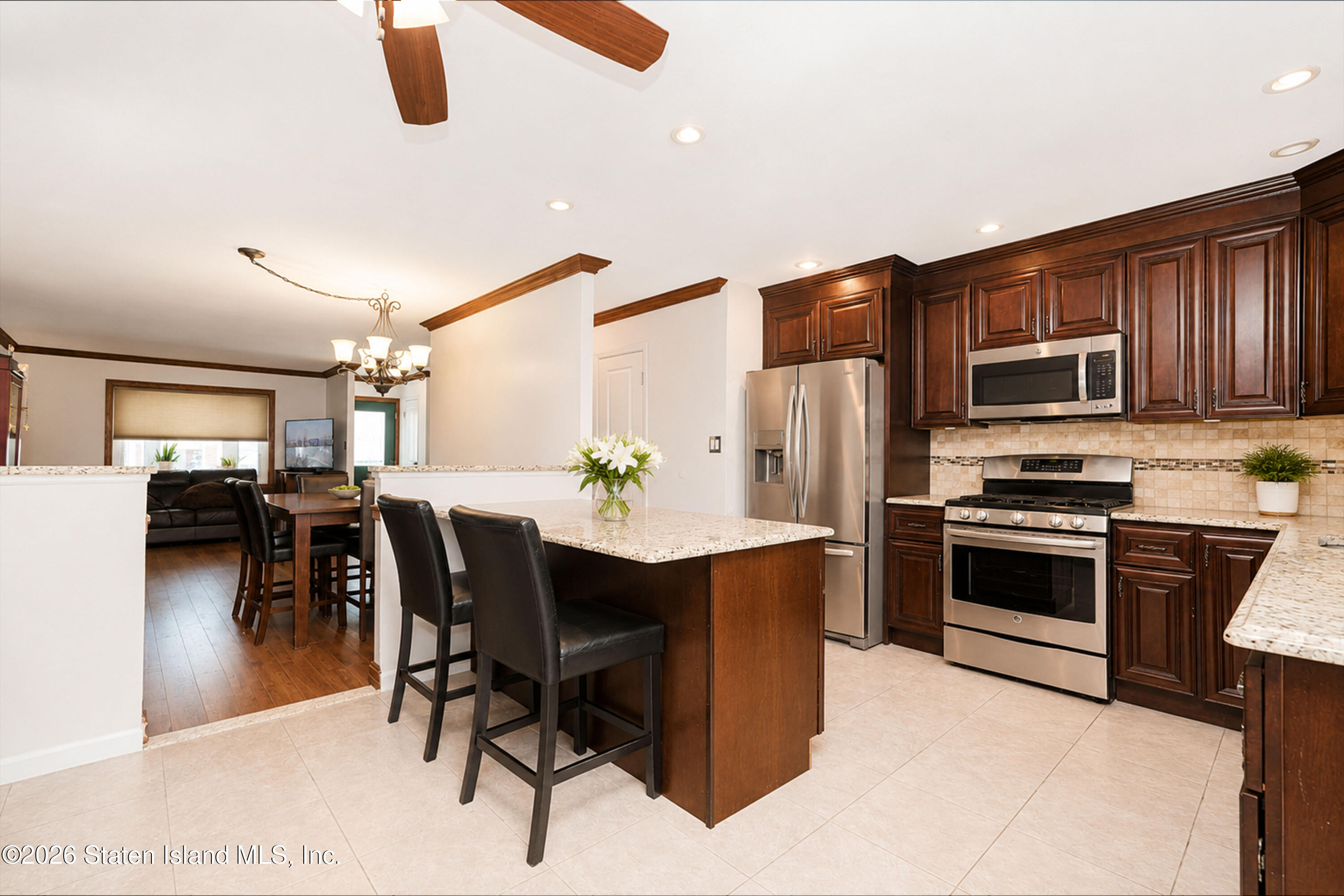 37 Middle Loop Road Staten Island, NY 10308 - Photo 16 of 38 a kitchen with stainless steel appliances kitchen island granite countertop a refrigerator a stove a sink a dining table and chairs with wooden floor