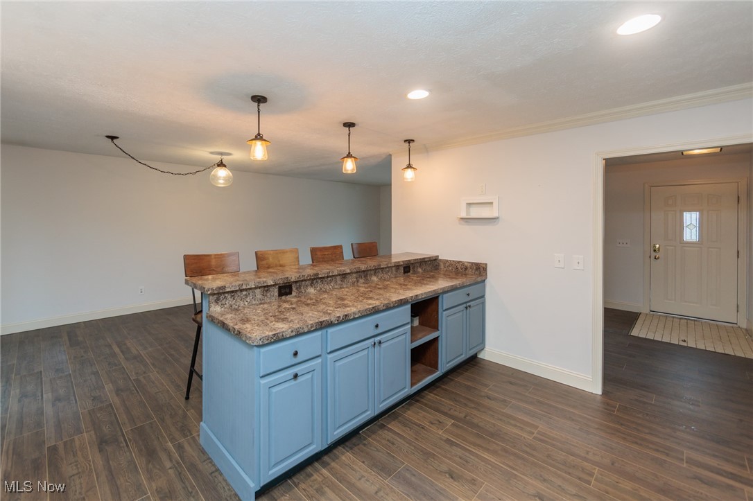 28013 Knickerbocker Road Bay Village, OH 44140 - Photo 12 of 38 Kitchen featuring blue cabinetry, a kitchen breakfast bar, wood tiled floors, hanging light fixtures, and recessed lighting