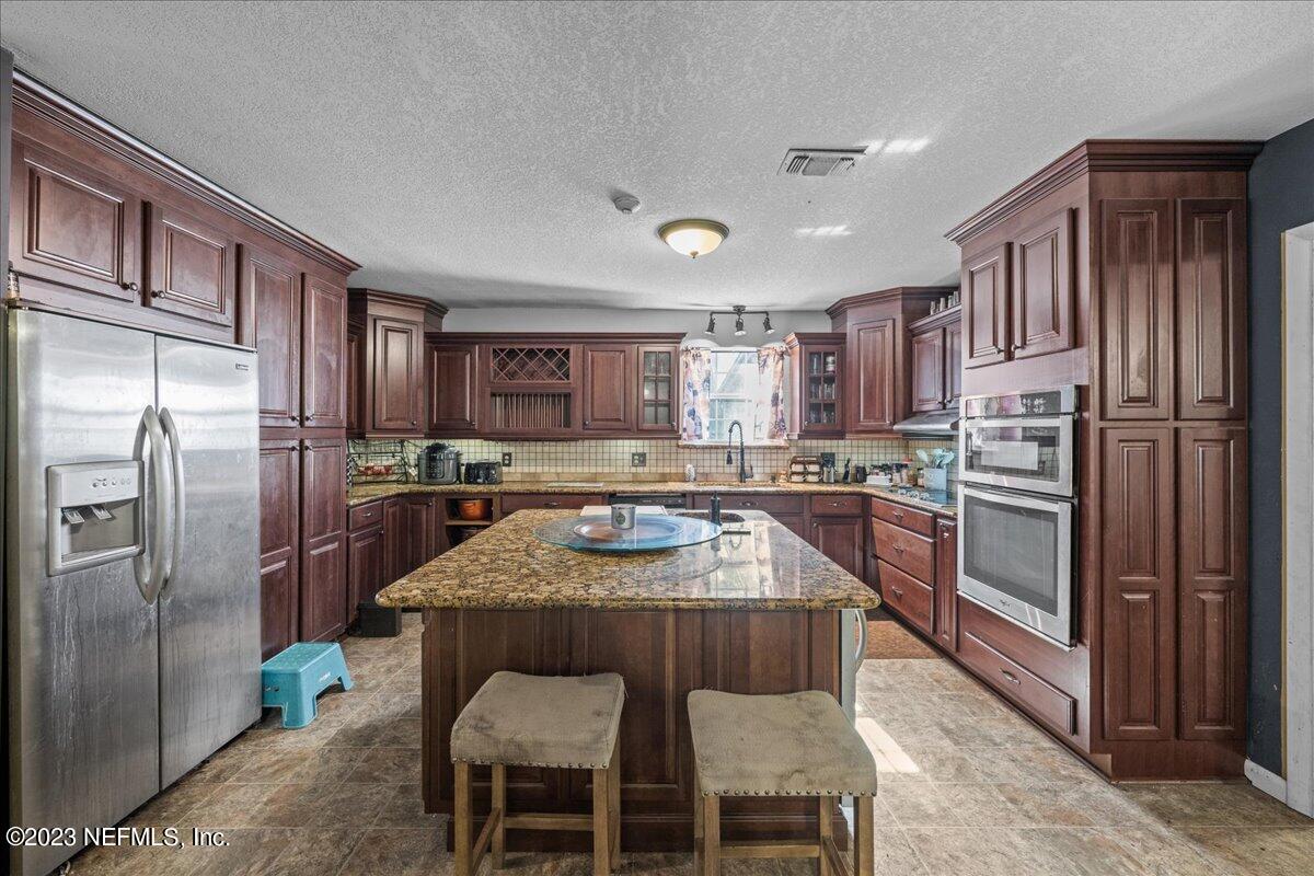 7145 Fitzpatrick Lane Jacksonville, FL 32226 - Photo 23 of 42 a kitchen with stainless steel appliances granite countertop a refrigerator a stove a sink a dining table and chairs