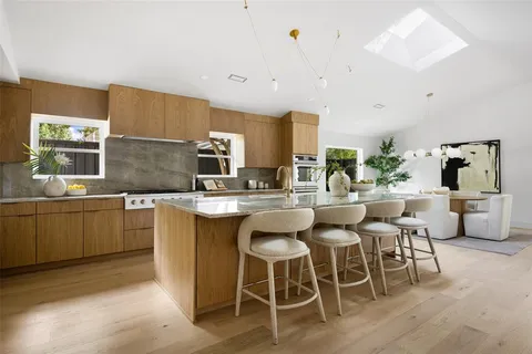 a kitchen with a dining table chairs sink and white cabinets