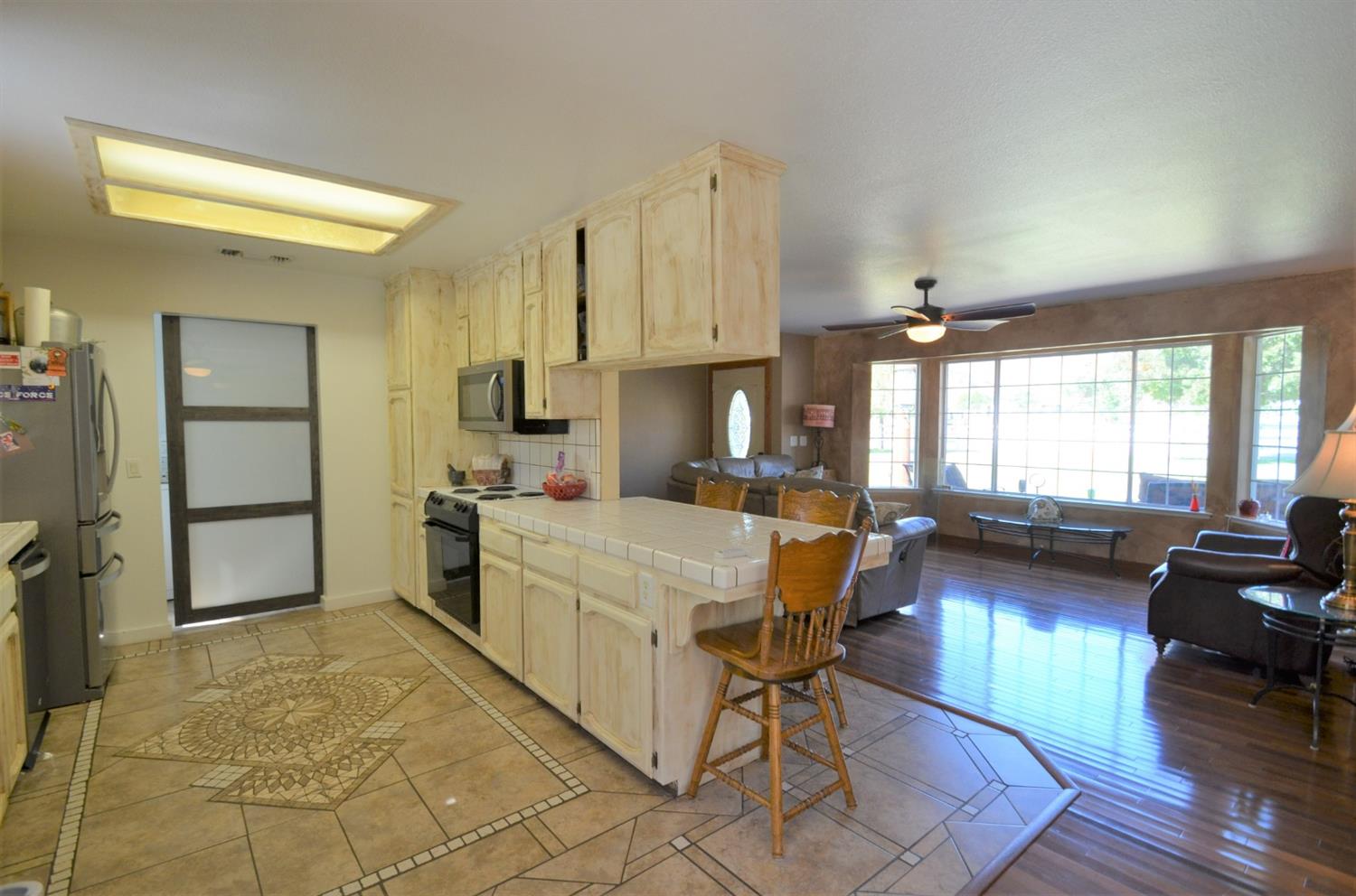 7453 Live Oak Drive Sanger, CA 93657 - Photo 10 of 28 a kitchen with stainless steel appliances kitchen island granite countertop a table chairs in it and a window