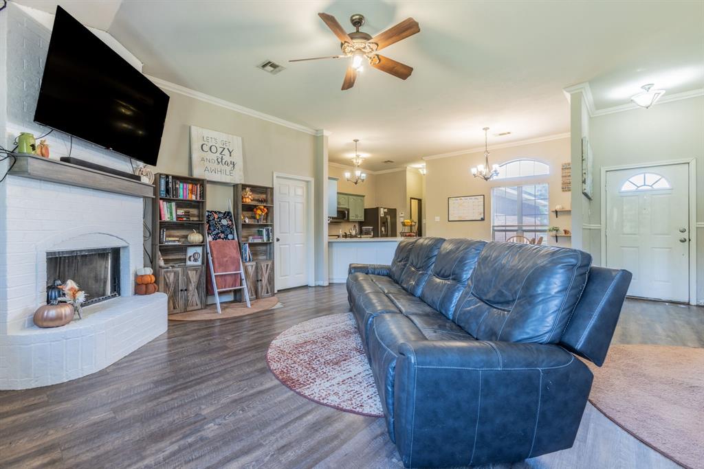 4930 Spring Valley Road Lorena, TX 76655 - Photo 5 of 34 Wood-finish flooring throughout, white brick fireplace with hearth, ceiling fan with integrated lighting, recessed lighting, and a front entry door with an arched window