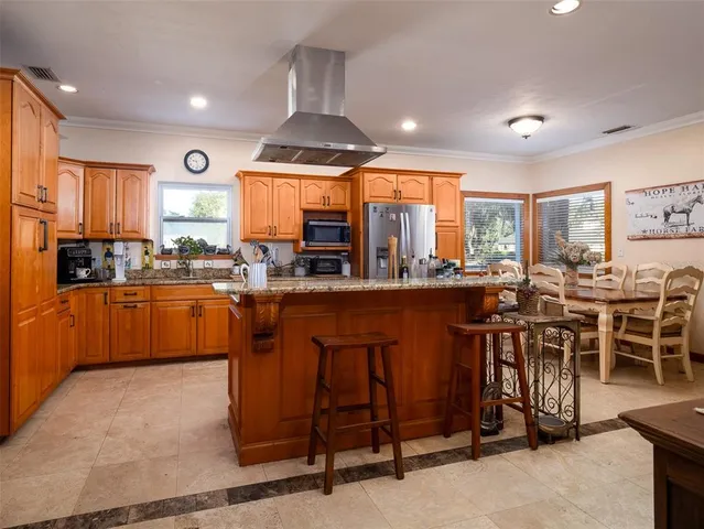a kitchen with stainless steel appliances kitchen island granite countertop a refrigerator and wooden cabinets