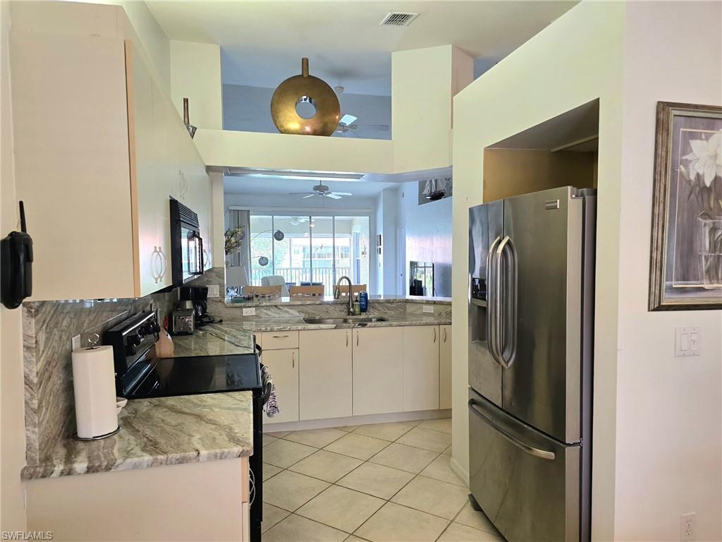 7436 Plumbago Bridge Road, Unit N202 Naples, FL 34109 - Photo 3 of 24 a kitchen with refrigerator and cabinets