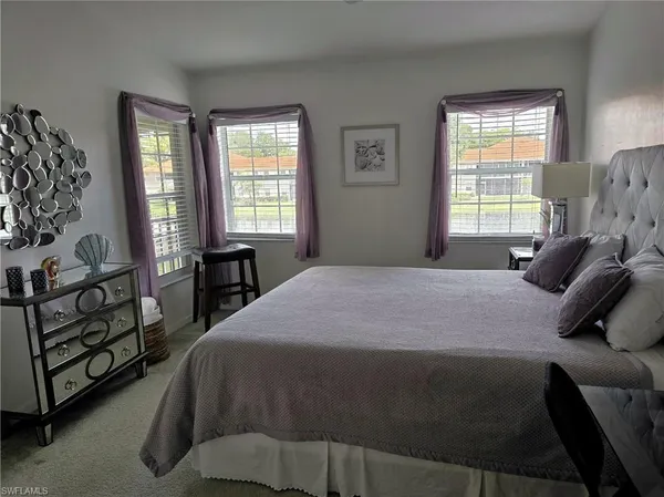 a bedroom with a bed a dresser with windows