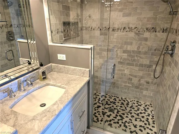 a bathroom with a granite countertop shower a sink and a mirror