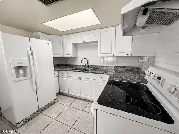 a kitchen with a refrigerator sink and cabinets