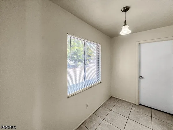 a view of an empty room with window and chandelier fan