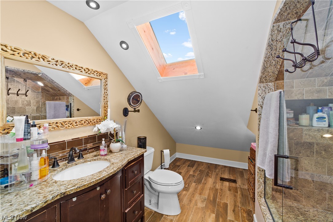 482 Trebisky Road Cleveland, OH 44143 - Photo 20 of 35 Bathroom featuring hardwood flooring, a shower with door, toilet, lofted ceiling with skylight, and large vanity