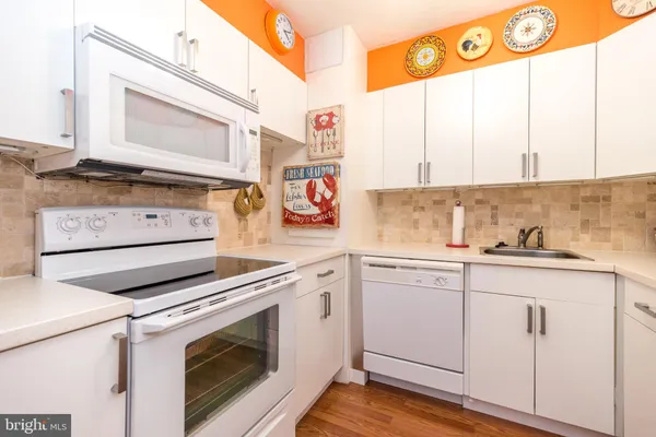 a kitchen with stainless steel appliances granite countertop white cabinets and white appliances