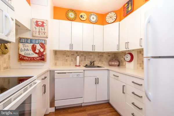 a kitchen with stainless steel appliances granite countertop a stove a sink and dishwasher with white cabinets