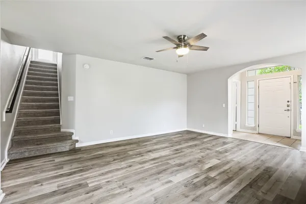 an empty room with wooden floor fan and windows