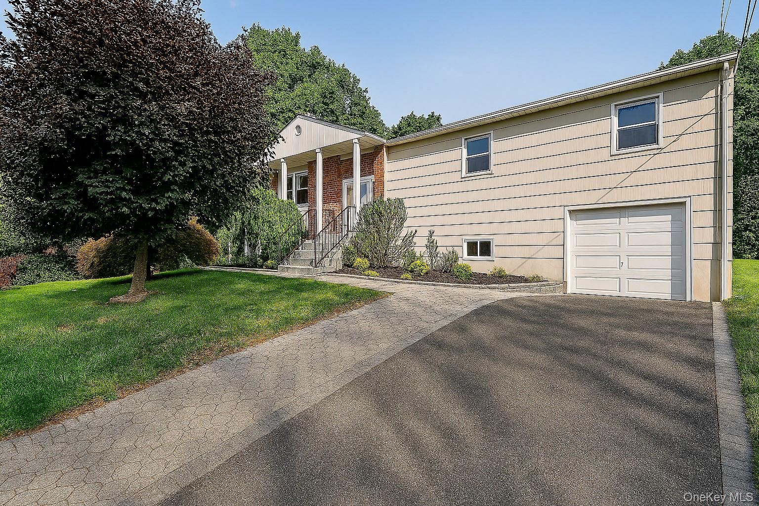 568 Manville Road, Unit UPPER R Pleasantville, NY 10570 - Photo 1 of 32 Raised Ranch featuring a brick facade with columned portico, an attached single-car garage, and a paved driveway