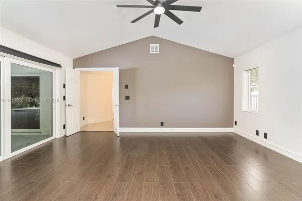 an empty room with wooden floor fan and windows