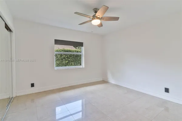 an empty room with a window and a ceiling fan