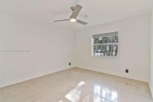 an empty room with a ceiling fan and window