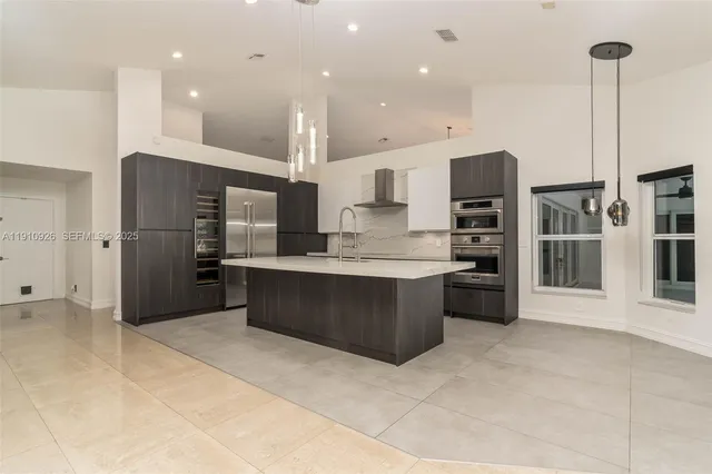 a large kitchen with stainless steel appliances kitchen island granite countertop a refrigerator a oven and a sink