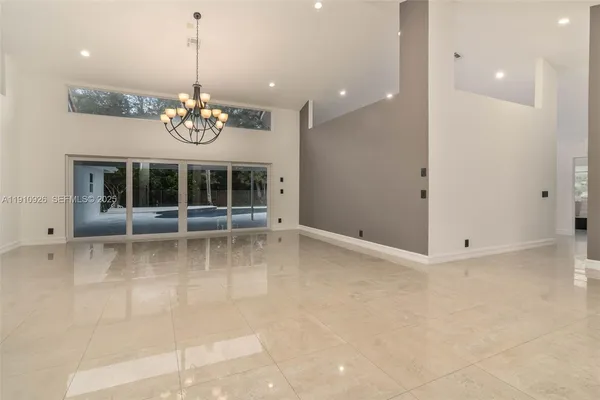 a view of a livingroom with a chandelier and kitchen view