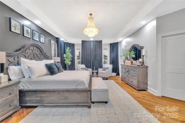 a spacious bedroom with a bed a chandelier and dresser