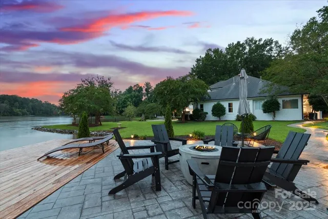 a view of a patio with table and chairs under an umbrella with large trees