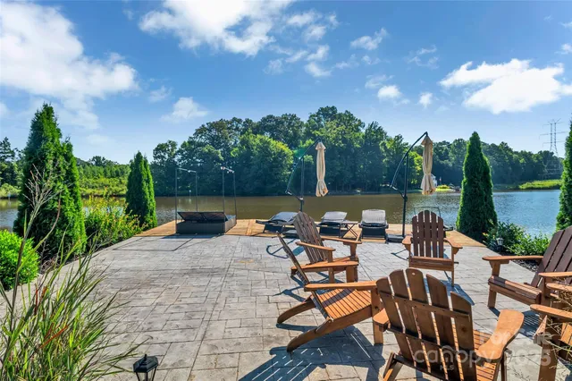 a view of a lake with table and chairs potted plants and lake view