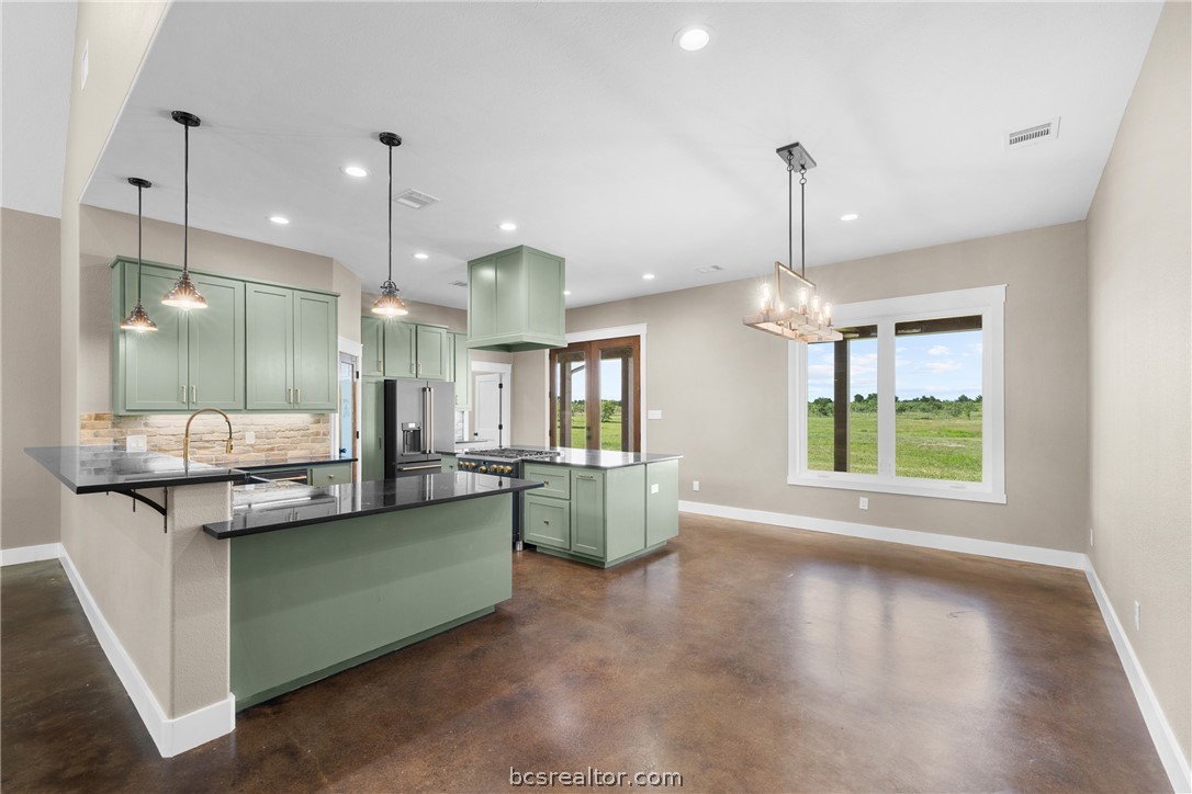 6951 Watermelon Road Somerville, TX 77879 - Photo 11 of 48 The kitchen offers a large center island, granite countertops, custom cabinetry, gas cooking, a walk-in pantry, and generous workspace, all flowing seamlessly into the dining and living areas.