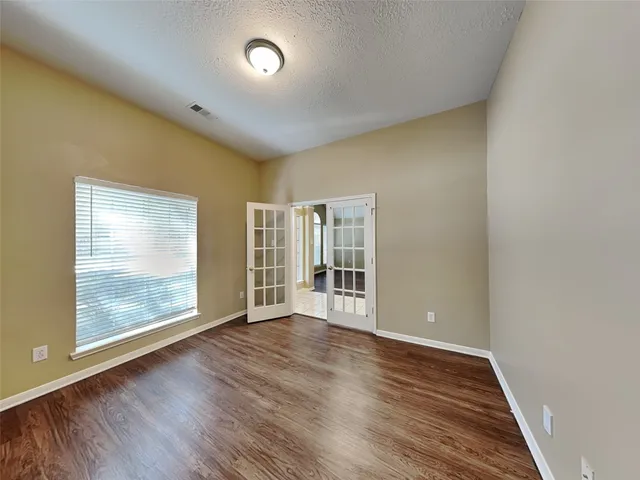 an empty room with wooden floor and windows