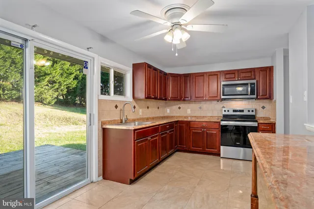 a large kitchen with stainless steel appliances granite countertop a stove top oven a sink and dishwasher a refrigerator with wooden floor