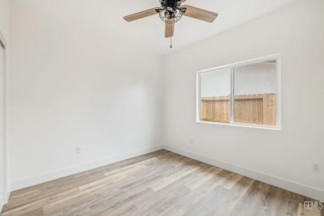 an empty room with a window and a fan