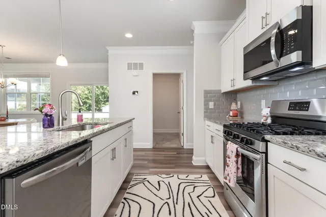 a kitchen with kitchen island white cabinets and stainless steel appliances