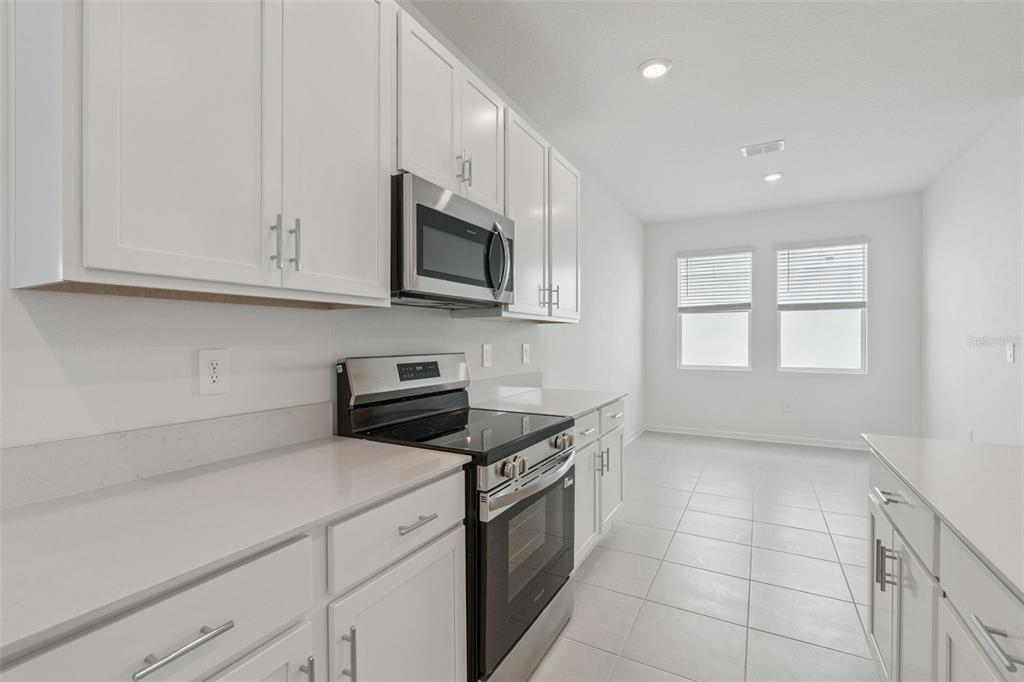 1672 Rider Rain Lane Apopka, FL 32703 - Photo 16 of 35 a kitchen with granite countertop white cabinets stainless steel appliances and window