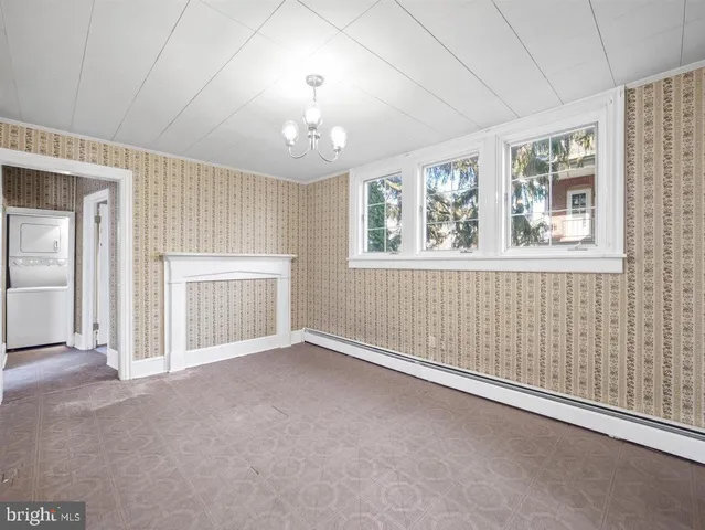 an empty room with chandelier fan and windows