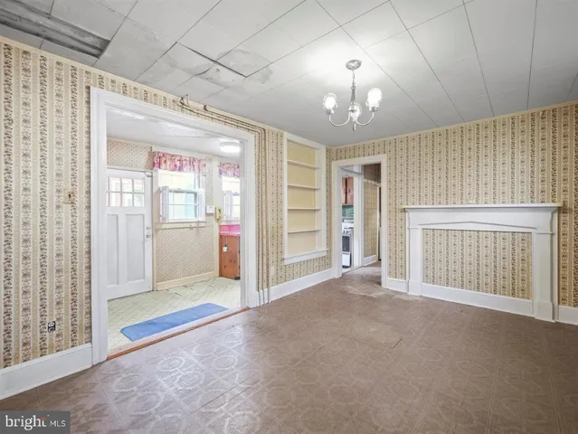 an empty room with chandelier fan and windows