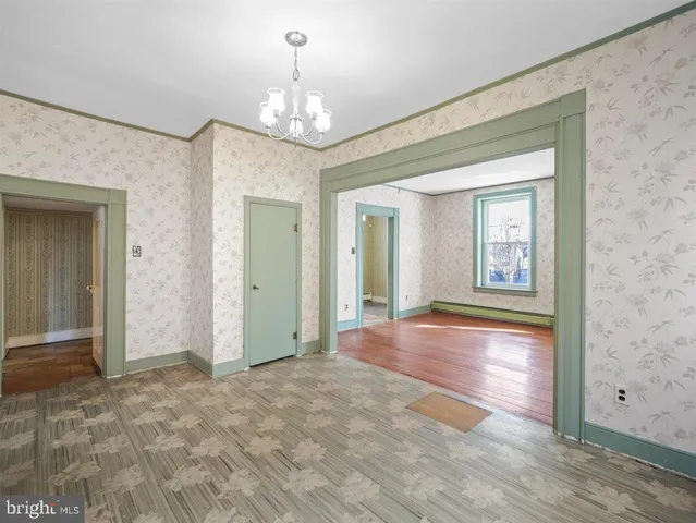 a view of a hallway with wooden floor and chandelier