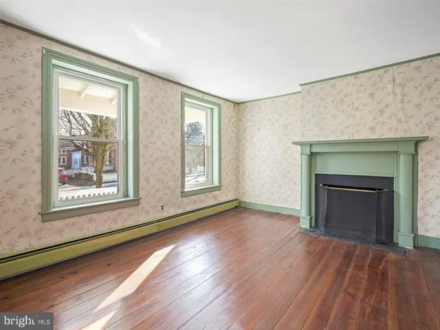 an empty room with wooden floor fireplace and windows
