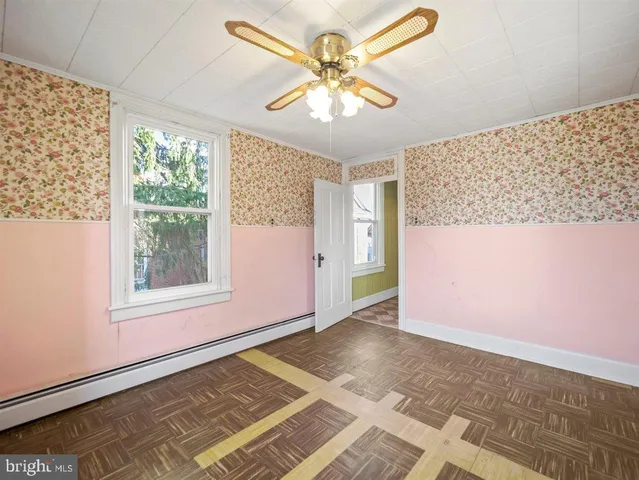 a view of an empty room with window and chandelier fan