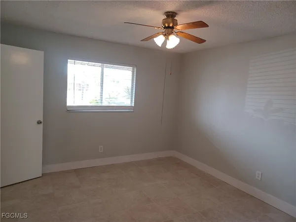 an empty room with a window and a fan