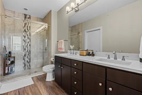 a spacious bathroom with a double vanity sink toilet mirror and shower