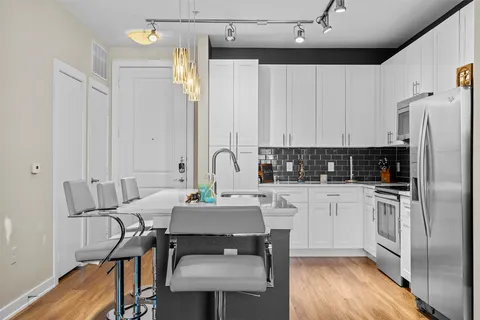 a kitchen with stainless steel appliances a stove a sink refrigerator and white cabinets with wooden floor
