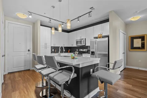 a view of a dining room with furniture a kitchen and chandelier