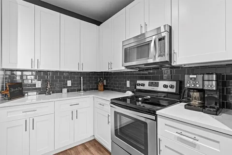 a kitchen with stainless steel appliances granite countertop white cabinets and a stove a oven with white countertops
