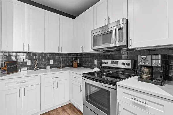a kitchen with stainless steel appliances granite countertop white cabinets and a stove a oven with white countertops